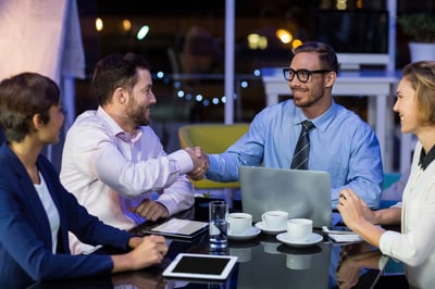 Businesspeople shaking hands while working in office at night